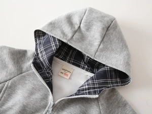 Detailansicht eines grauen Jungen-Hoodies mit klassischem schwarz-weißem Karofutter