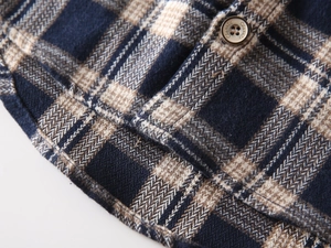 Detailed close-up of plaid flannel shirt hem showing stitching and a classic button
