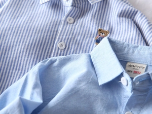 Détail de chemises oxford en coton pour garçons avec rayures et broderie d'ourson