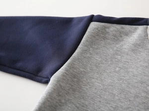 Détail de couture sur manche bleu marine et gris d'un sweat en coton pour garçon