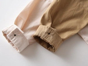 Détail des poignets boutonnés sur des chemises en coton à manches longues beige