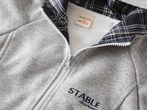 Detailaufnahme grauer Kinder-Hoodie mit kariertem Futter und blauer Stickerei am Kragen