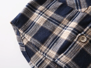 Detail of blue and beige plaid children shirt featuring classic engraved buttons