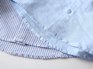 Détail de la chemise Oxford pour garçon montrant l'ourlet rayé et les coutures fines