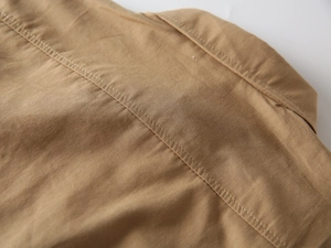 Gros plan d'une chemise kaki en coton pour garçon avec coutures et texture détaillées