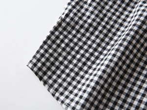 Detail of black and white gingham shirt hem showing fine stitching on premium fabric