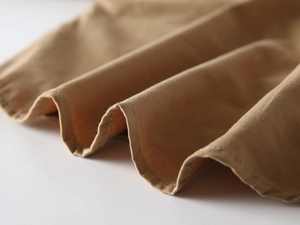 Détail du tissu en coton sergé kaki et des coutures sur l'ourlet de la chemise