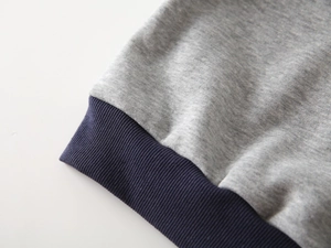 Gros plan du tissu en maille grise et des poignets côtelés marine du sweat garçon