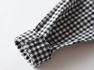 Close-up of black and white gingham shirt cuff showing fine texture and stitching