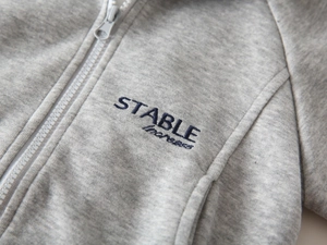 Detailansicht graue Jungen-Sweatjacke mit dunkelblauer Stickerei und hochwertigem Metallreißverschluss