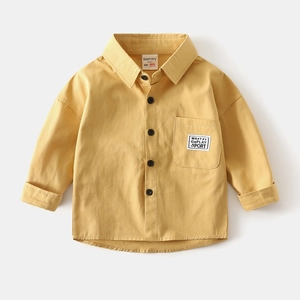 Detail of a bright yellow boy's cotton shirt featuring a chest pocket and text label