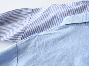 Gros plan d'une chemise pour garçon en coton Oxford avec coutures fines et col rayé bleu