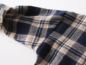 Macro detail of navy and beige plaid flannel fabric with soft brushed texture and fine stitching