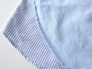 Vue macro détaillée du tissu en coton Oxford bleu et des coutures fines de la chemise garçon
