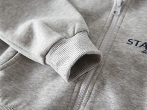 Detailansicht der grauen Strickjacke für Jungen mit Rippbündchen und Reißverschluss