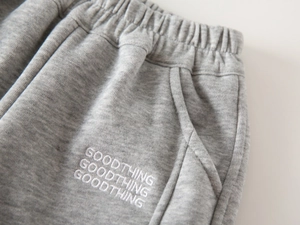 Detail of grey joggers featuring Goodthing embroidery and elastic waist with pockets