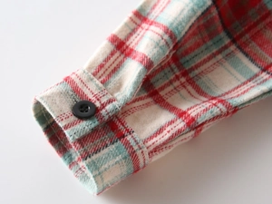 Dettaglio del polsino della camicia di flanella a quadri con bottone nero
