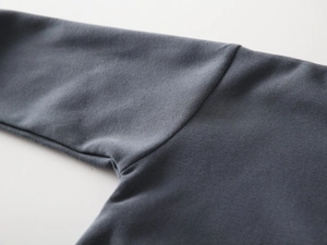Detailed close-up of charcoal gray knit fabric seams and soft cotton texture of child sweatshirt