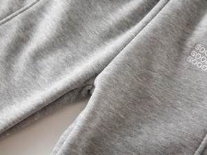 Macro shot of gray cotton fleece jogger pants with white triple GOOD embroidery