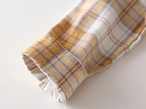 Close-up of flannel shirt cuff featuring yellow and brown plaid patterns and neat stitching