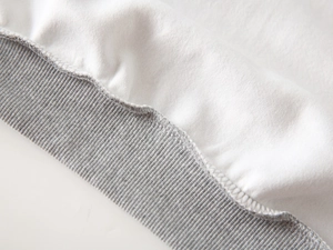 Nahaufnahme der grauen Rippbündchen und weißen Baumwollnähte an der Jungen-Zipperjacke