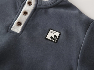 Detail of dark blue kids' knit henley sweatshirt with retro buttons and logo patch