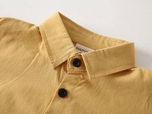 Macro shot of ginger yellow cotton linen shirt collar with black buttons and woven label