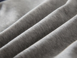 Gros plan du tissu tricoté gris avec plis souples sur le sweat polaire pour garçon