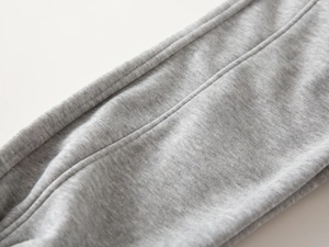 Macro view of gray knitted fabric with durable double-needle stitching on winter pants