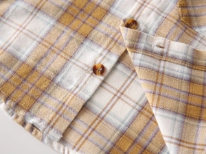 Detail of yellow plaid cotton shirt with soft brushed fabric and amber buttons