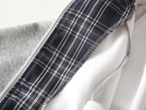 Detail der Jungen-Kapuzenjacke mit weißem Harzreißverschluss und schwarz-weißem Karoband