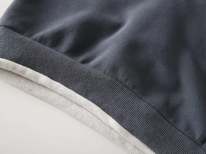 Detailed close-up of double-layered ribbed cuffs on navy blue knitted cotton sweater
