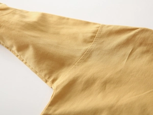 Detail of armhole stitching and twill fabric texture on ginger yellow boys shirt