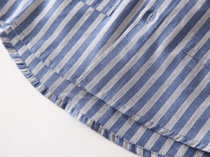 Makro-Detail des blau gestreiften Baumwollhemdes mit präziser Naht am abgerundeten Saum