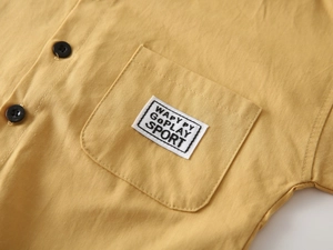 Detail of yellow cotton shirt showing chest pocket with woven label and fabric texture