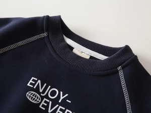 Detail of ribbed crew neck and white contrast stitching on boy's navy fleece sweatshirt