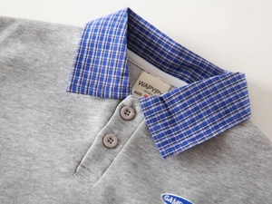 Detail of baby boys polo shirt featuring a checkered collar and soft knit fabric texture
