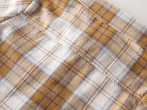 Close-up of yellow plaid fabric with high-quality double-needle stitching on boys shirt