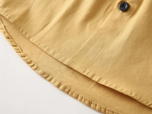 Detailed macro view of ginger yellow boy shirt showing fabric texture and curved hemline