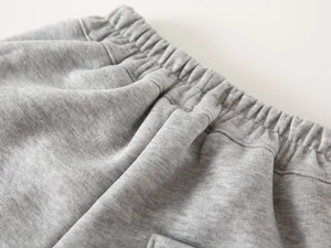 Detailed close-up of grey marl knit sweatpants with elastic waistband and stitching
