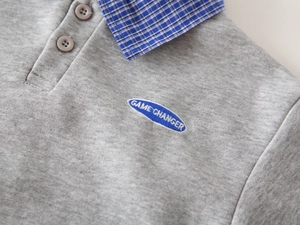 Close-up of boys' grey Polo shirt with plaid collar and Game Changer embroidery