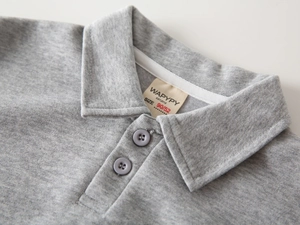 Détail du col d'un sweat polo gris avec boutons et étiquette de taille tissée