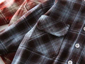Detailaufnahme der Flanell-Karohemd-Textur mit Pattentasche und Kontrastknöpfen