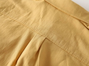 Detail of the high-quality stitching and fabric texture on a boys yellow cotton shirt