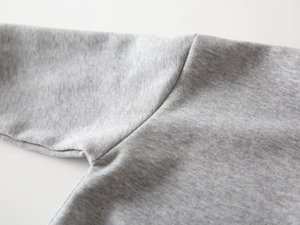 Gros plan sur le tricot de coton gris et les coutures détaillées du sweat pour enfant