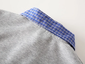 Detailed view of kids knit polo shirt with blue plaid collar and soft grey fabric