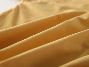 Macro detail of high-quality bright yellow cotton fabric texture on boys' long-sleeve shirt