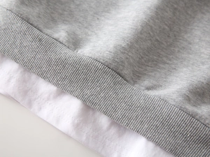 Détail de l'ourlet du sweat-shirt gris pour garçon avec effet de superposition blanc