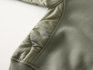 Detail of olive green boys sweatshirt showing diamond quilted fabric and ribbed cuff hem