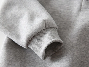 Détail du poignet côtelé sur un sweat-shirt pour garçon en coton gris chiné doux